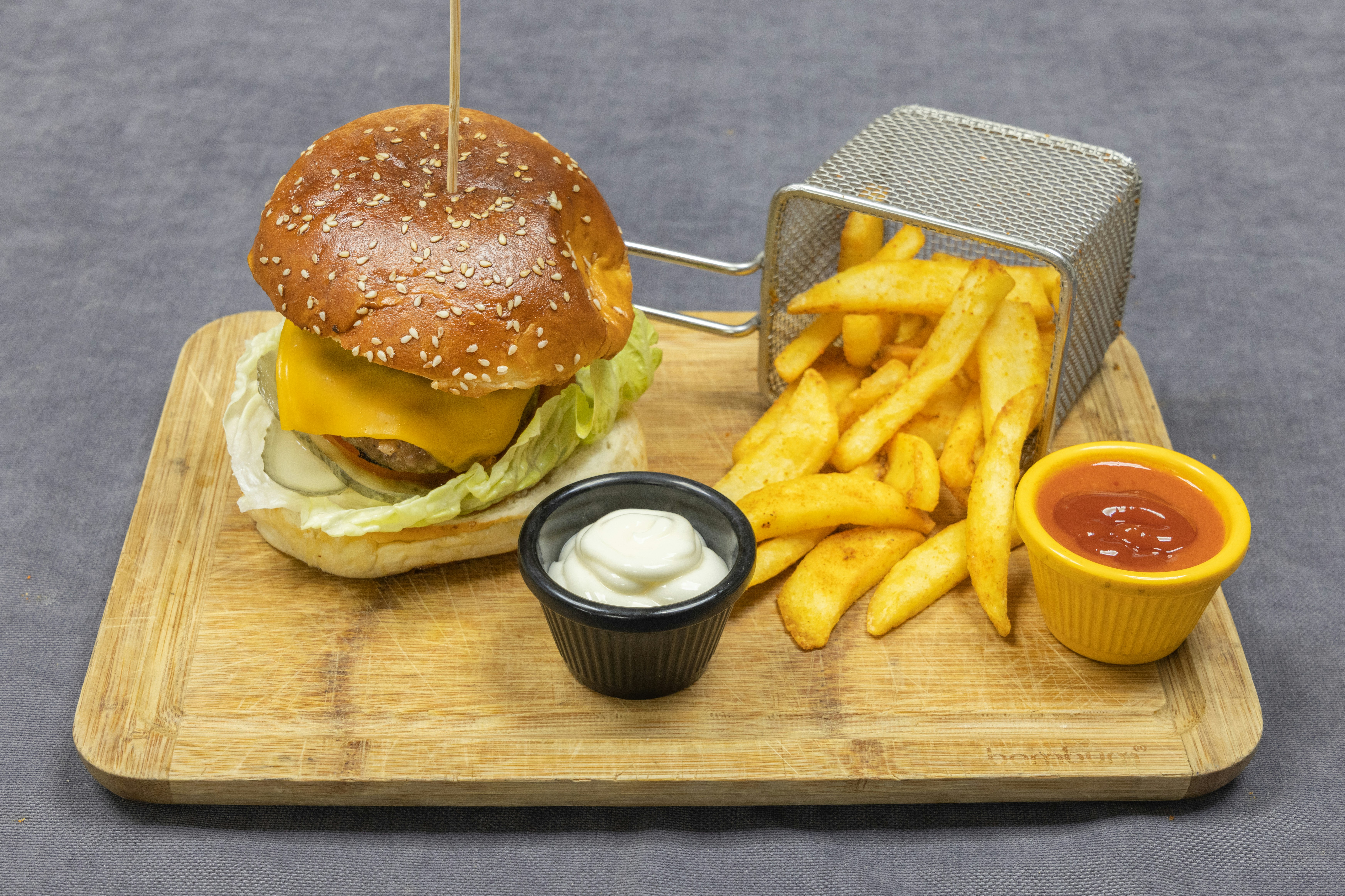 burger and fries on brown wooden chopping board